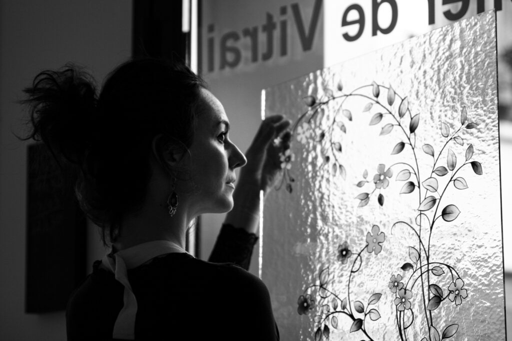 Marie Grillo, créatrice de vitraux, de profil devant un vitrail peint dans son atelier parisien